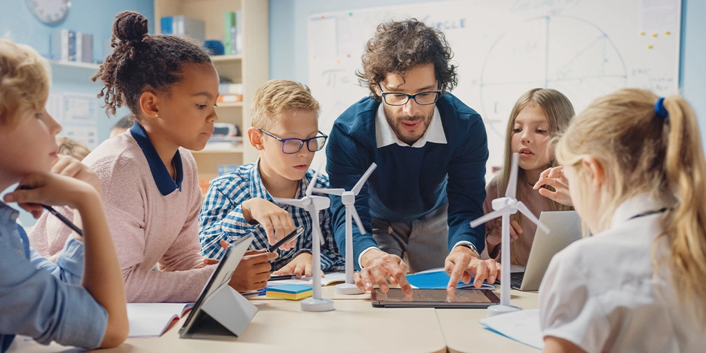 A diverse group of children, including some with autism, are working together on a science project with a teacher. 